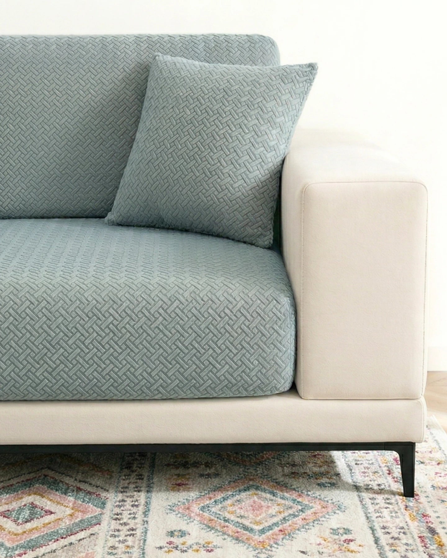 Gray textured sofa with a matching pillow on a colorful rug