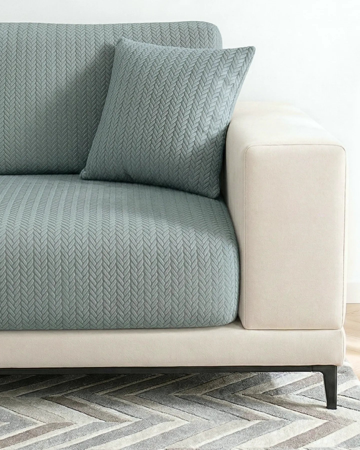 Green textured sofa with a matching pillow on a neutral background