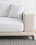 Beige sofa with white  textured cushions on a neutral background
