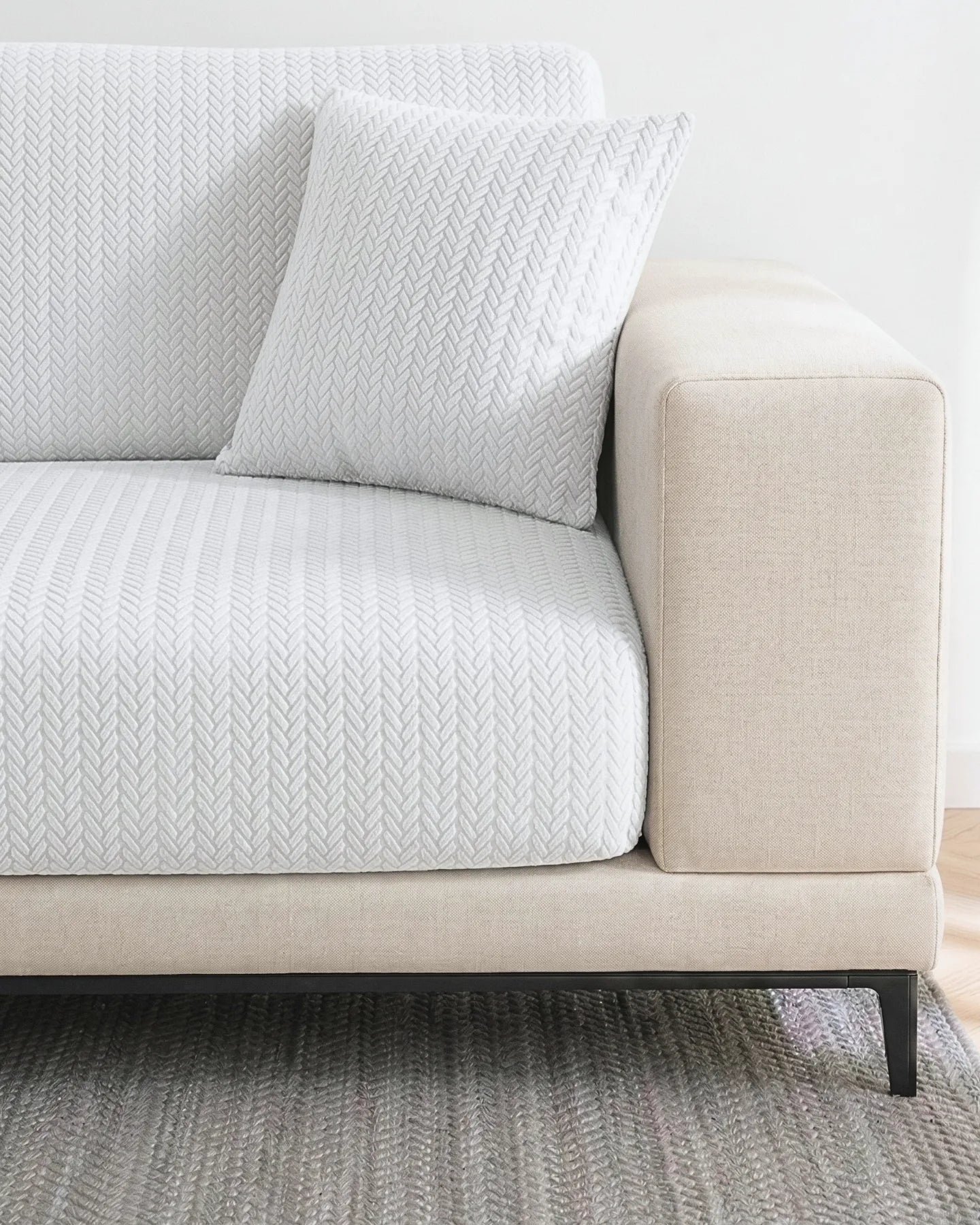Beige sofa with white  textured cushions on a neutral background