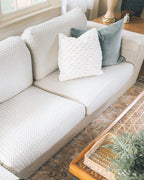 Beige Sofa with White textured Cushions and Pillows as decoration, in a bright living room