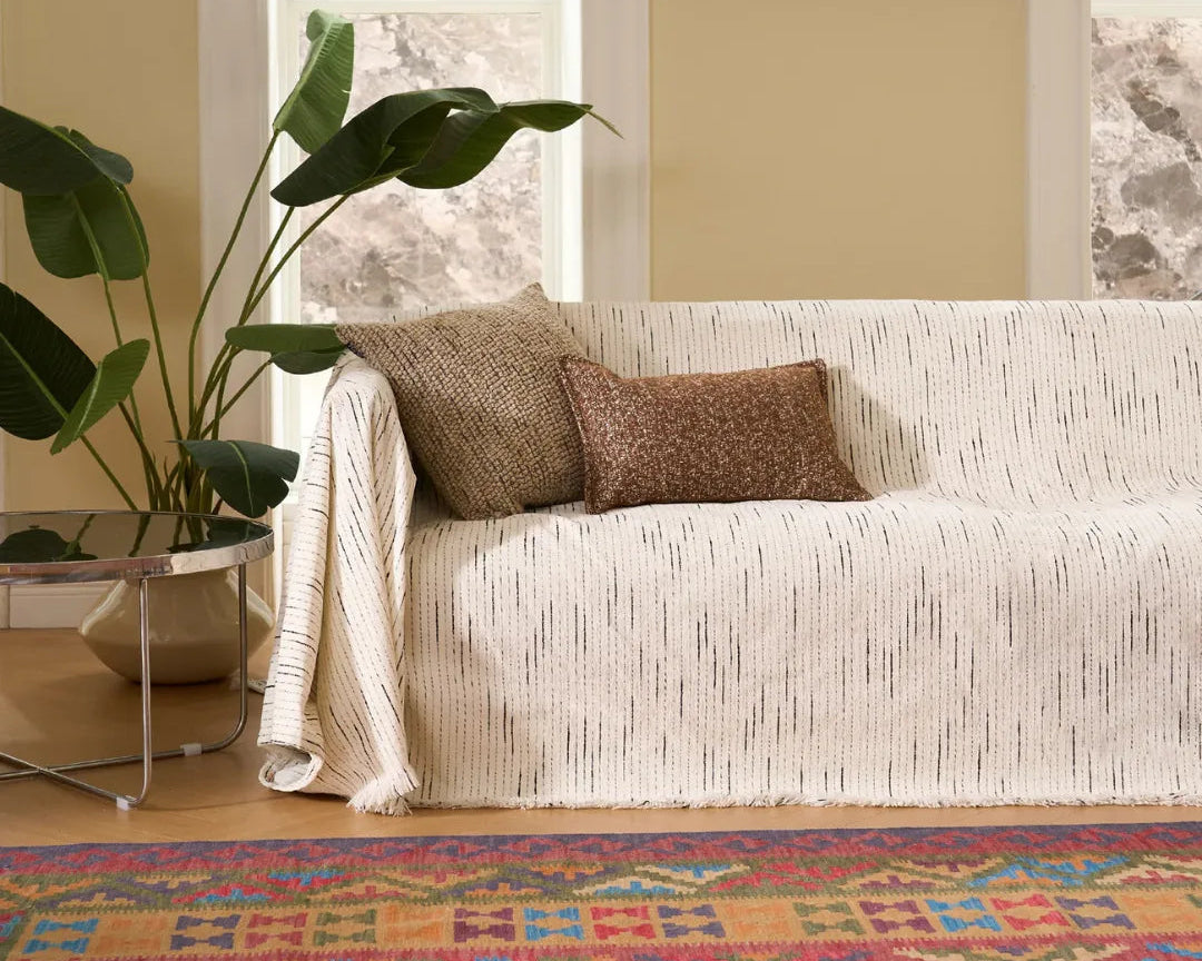 Living room with a white sofa, patterned rug, and plant